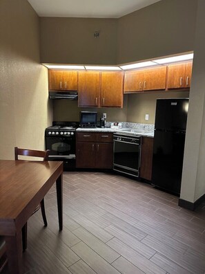Une cuisine compacte avec des meubles en bois, une cuisinière, un four, un four à micro-ondes et un réfrigérateur.