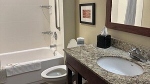 A bathroom with a bathtub, toilet, sink, and a mirror.