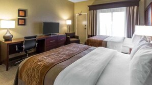 A hotel room with two beds, a desk with a chair, a television, and a window with curtains.