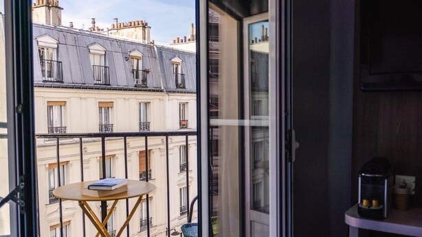Un balcón con una mesa, una silla y vistas a edificios cercanos.