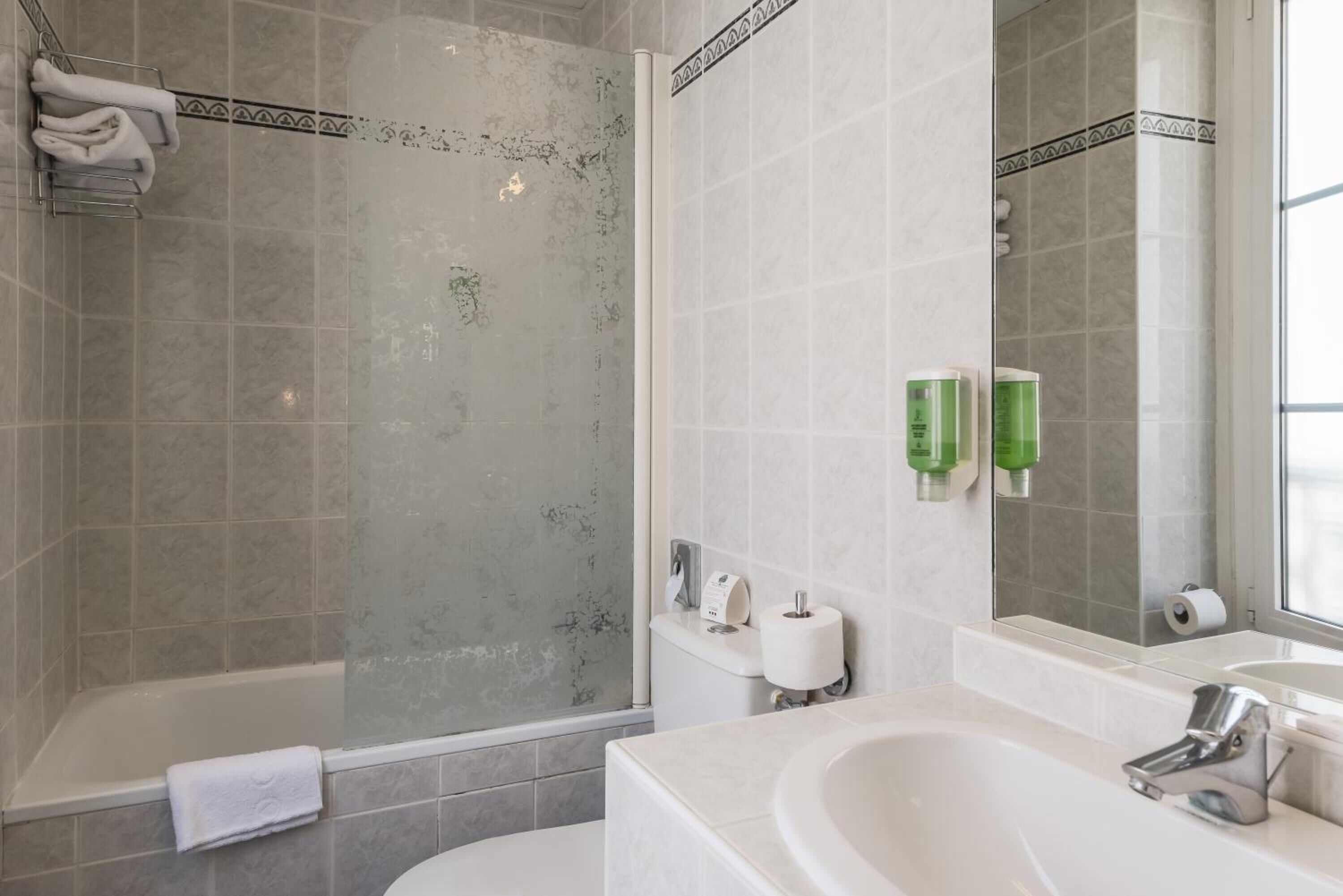 A bathroom with a shower, toilet, sink, and mirror.