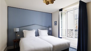 Habitación de hotel con una cama grande, una mesita de noche, una lámpara, una ventana con cortinas y vistas al exterior.