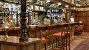 A bar area with wooden bar stools, a variety of liquor bottles, and a selection of glasses. - The Bell In Driffield (Driffield)
