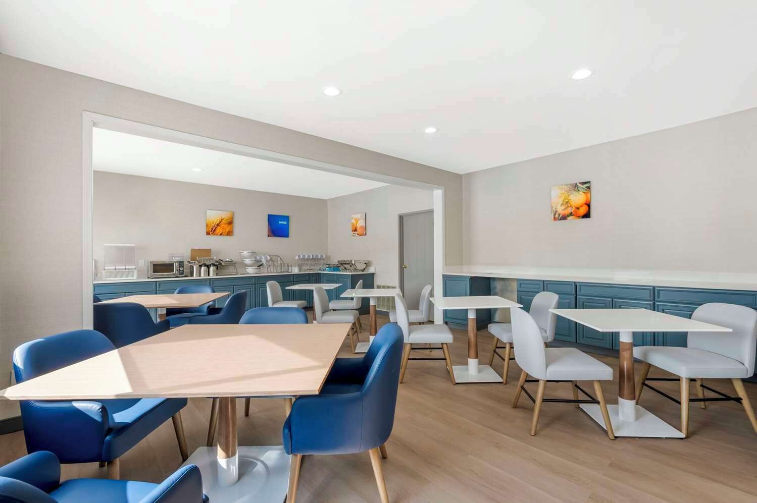 A modern dining area with blue and white chairs, a central table, and a kitchen in the background.