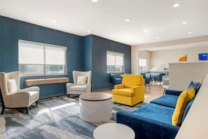 A modern living area with a blue accent wall, a yellow armchair, a blue sofa, and a round coffee table.