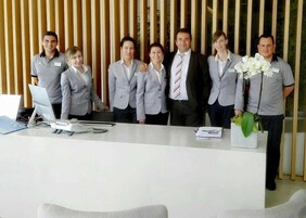 Un mostrador de recepción con una computadora portátil, documentos y un florero.