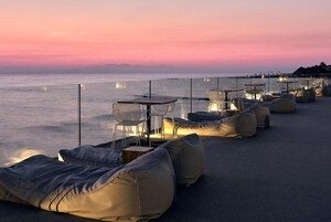 Una terraza frente al mar con mesas y sillas al aire libre, con vistas al océano.