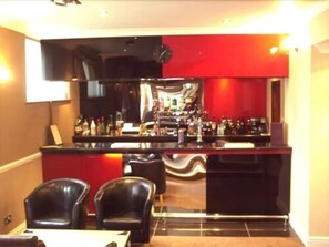 A bar area with a counter, chairs, and a television. - Mayfair Hotel - Oceana Collection (Bournemouth)