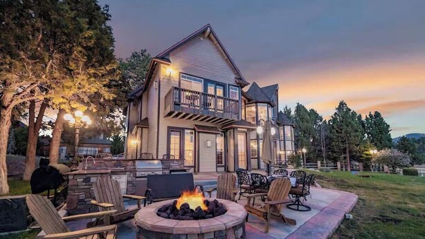 A two-story house with a stone fire pit, outdoor seating, and a balcony. - Big Bear Lakefront Luxury Home w/ Spa & Views (Big Bear Lake)