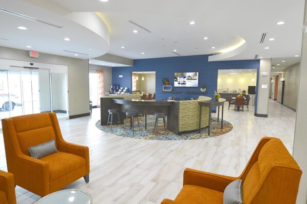 Vestíbulo de hotel con recepción, zona de estar y vistas al exterior.