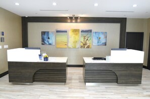 Un área de recepción con dos mostradores, una exhibición de arte en la pared y una puerta a la derecha.