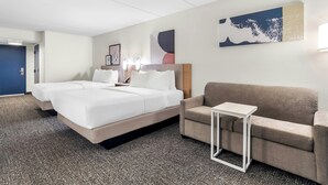Une chambre d’hôtel avec un lit, un canapé, une petite table et des œuvres d’art accrochées aux murs.