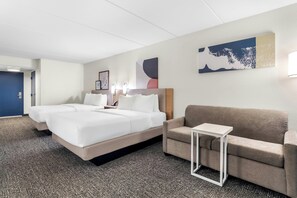 A hotel room with a bed, a sofa, a small table, and artwork on the walls. - Spark by Hilton Kimball (Jasper)