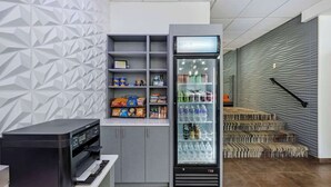 Un kiosque en libre-service équipé d’un distributeur de boissons, d’une imprimante et d’un mur orné de motifs géométriques.