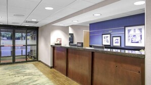 A reception area with a counter, a blue wall with framed pictures, and a carpeted floor. - Chicago Elgin / I-90, IL (Elgin)