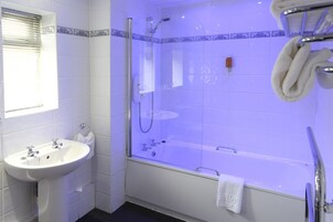 A bathroom with a sink, a glass-enclosed shower, and a bathtub.