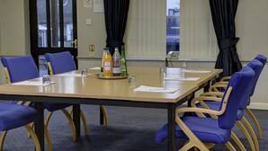 A conference room with a long table, blue chairs, and water bottles on the table. - Park Hall Hotel (Chorley)