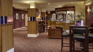 A hotel lobby with a bar area, seating, and a patterned carpet. - Park Hall Hotel (Chorley)
