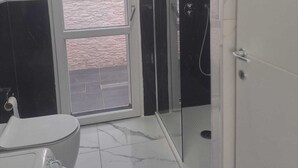 Un bany amb vàter, dutxa i finestra.