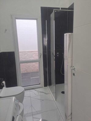 Ein Badezimmer mit Toilette, Dusche und Fenster.