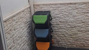 Un angle d'una habitació amb una paret de pedra, una paret blanca i un sòl negre.