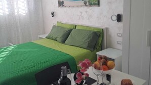 Habitació d'hotel amb un llit, una taula de menjador amb articles per esmorzar, un quadre a la paret i una finestra amb cortines.