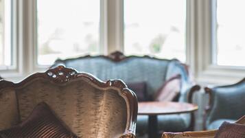 A room with a vintage sofa, a small round table, and large windows.
