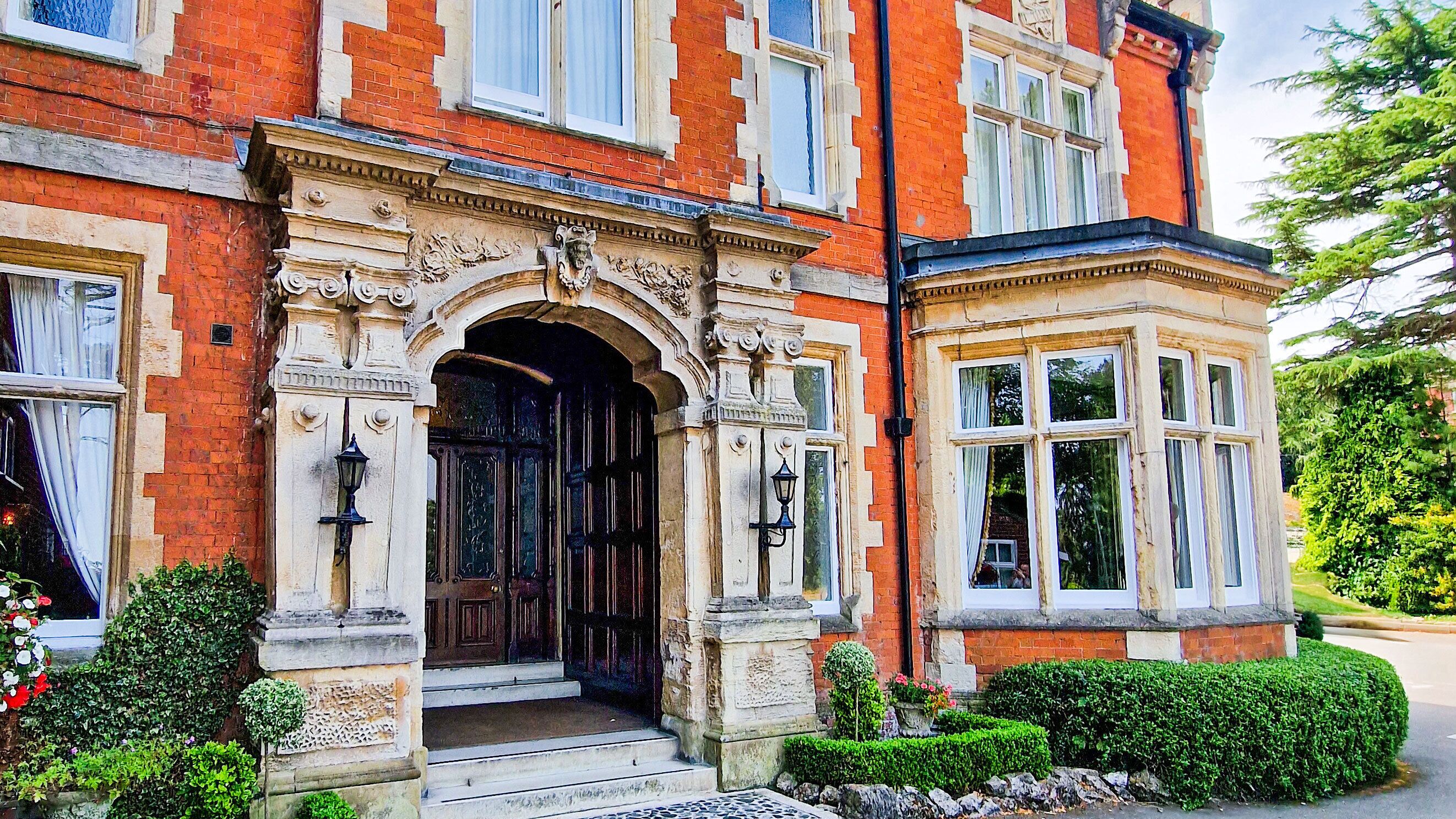A red brick building with a large arched entrance, stone steps, and a corner bay window.