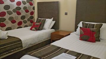 A hotel room with two beds, each with a pillow and a wooden nightstand.