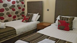 A hotel room with two beds, each with a pillow and a wooden nightstand. - CBH Oaklands Hall Hotel (Grimsby)