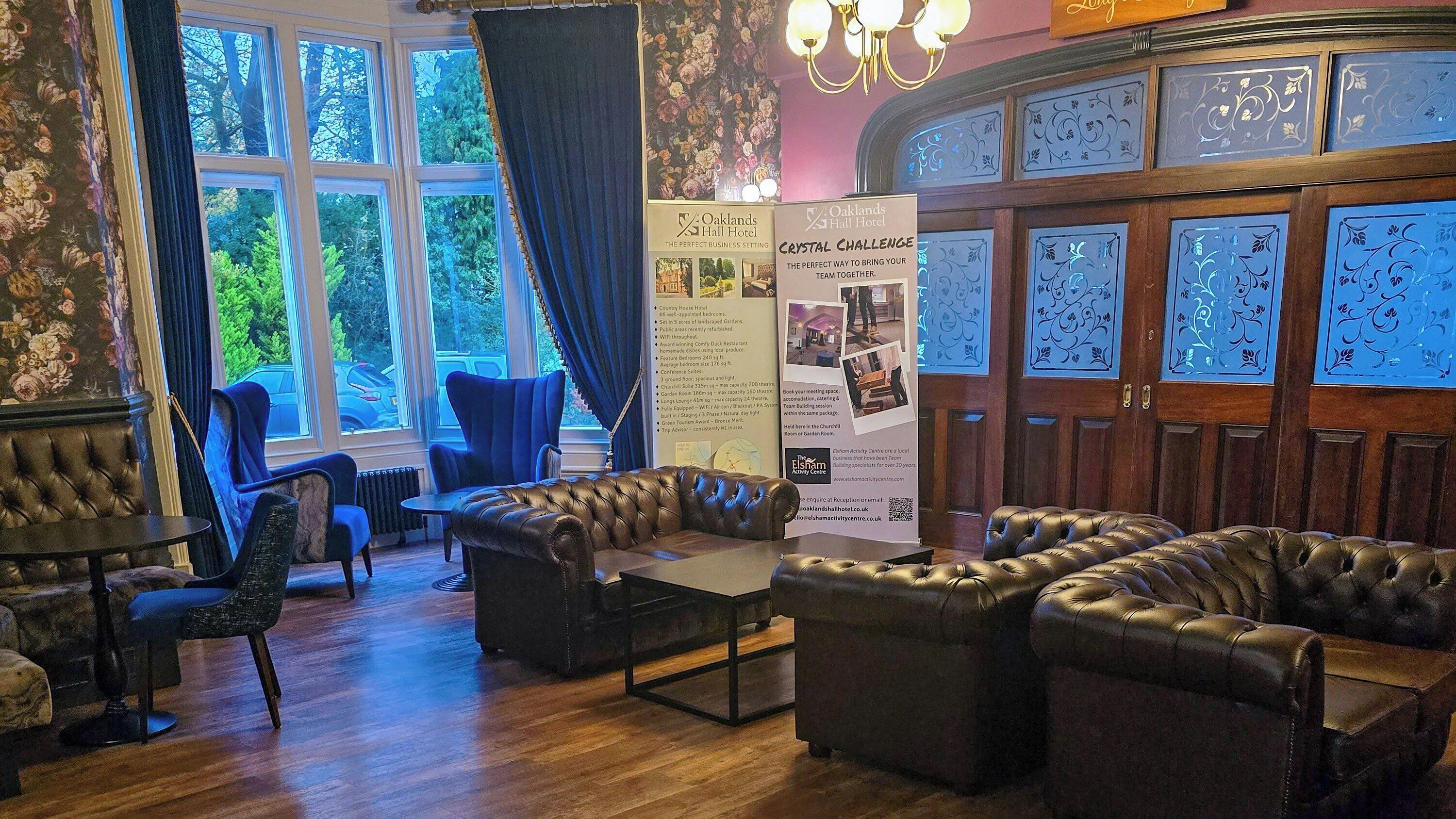 A hotel lobby with leather sofas, a reception desk, and a large window with curtains.