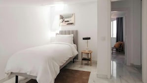 A bedroom with a bed, bedside table, lamp, and a painting on the wall. - Sonder Santa Ana (Madrid)