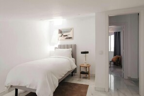 A bedroom with a bed, bedside table, lamp, and a painting on the wall. - Sonder Santa Ana (Madrid)