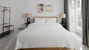 A hotel room with a bed, two bedside tables, a wardrobe, and two wall-mounted paintings. - Sonder Santa Ana (Madrid)