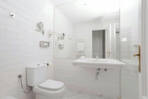 A modern bathroom with a toilet, bidet, and sink. - Sonder Santa Ana (Madrid)