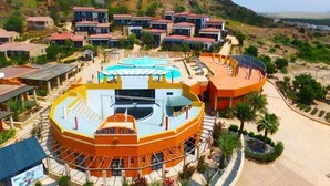 Ein Resort mit einem zentralen, kreisförmigen Gebäude, einem Swimmingpool und mehreren Gästevillen.