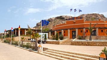 Ein Gebäude mit einem Schild, auf dem 'MARINE CLUB' steht, und mehreren Flaggen, darunter die Flagge der Europäischen Union.