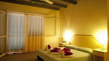 A hotel room with a bed, a bedside table, a nightstand, a ceiling fan, and curtains.