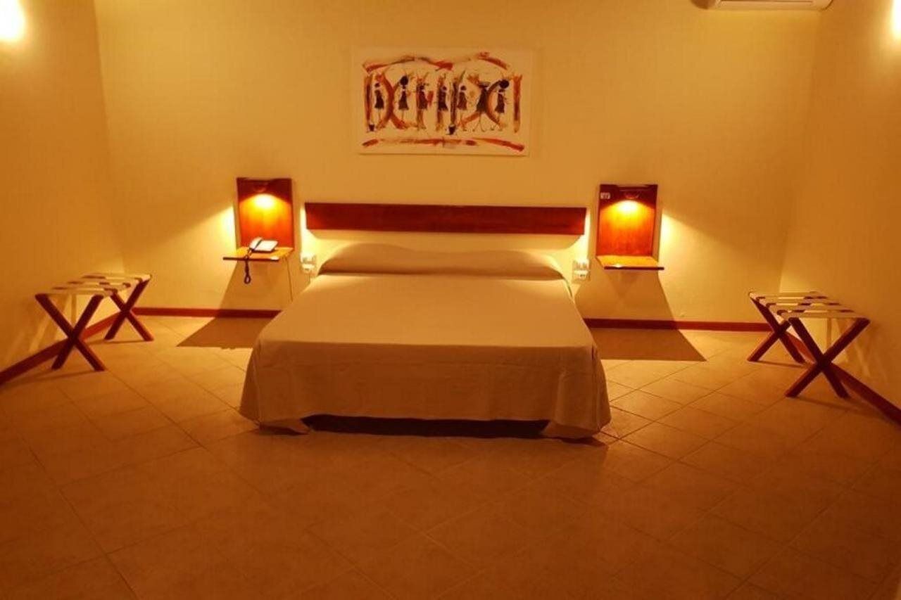 A hotel room with a bed, bedside lamps, and a wall-mounted artwork.