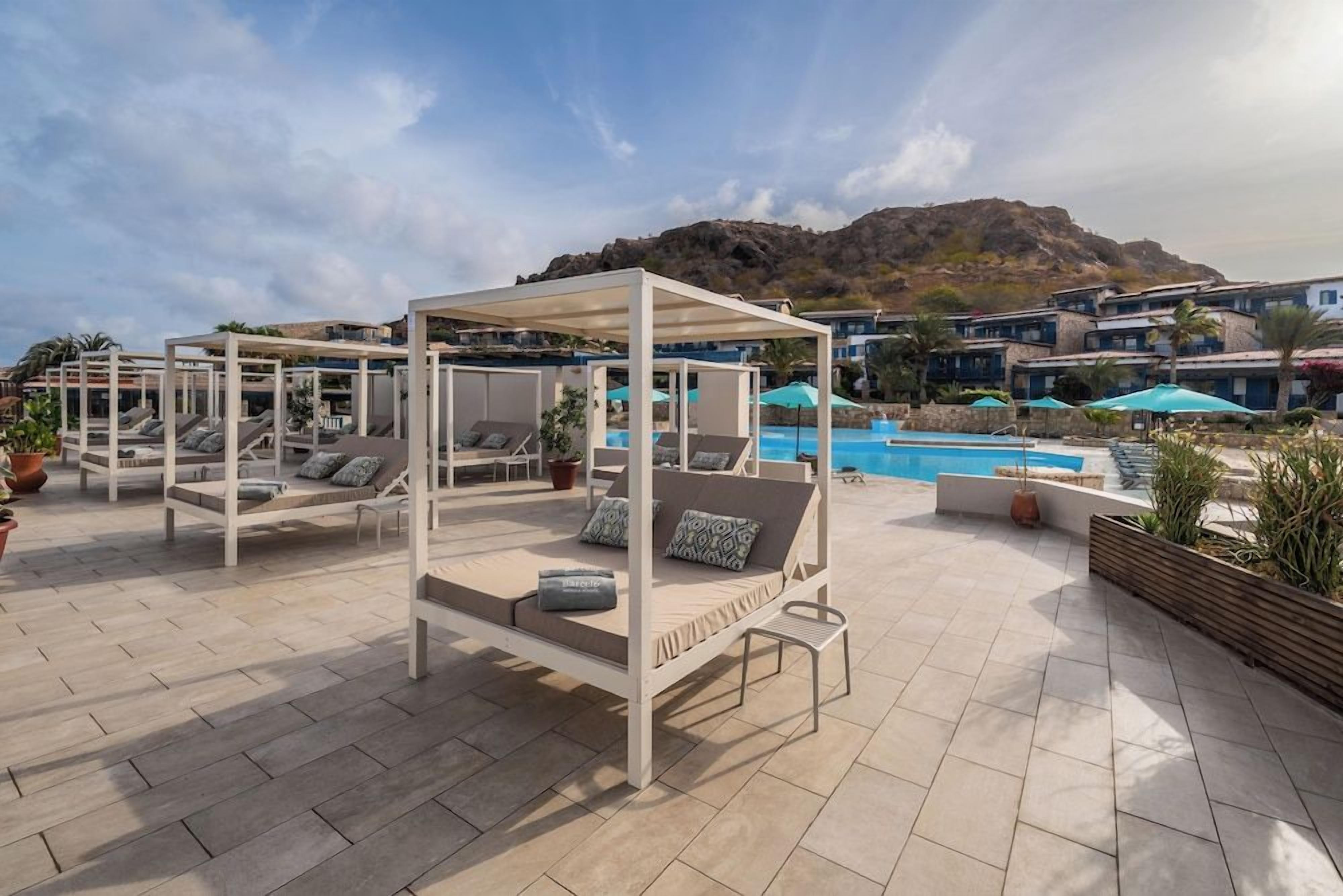A rooftop pool area with sun loungers and a pergola structure.