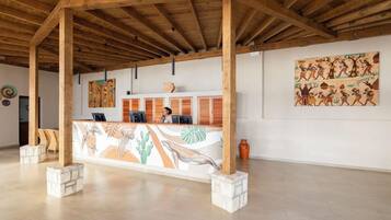 A reception area with a wooden ceiling, a reception desk with a mural, and artwork on the walls.
