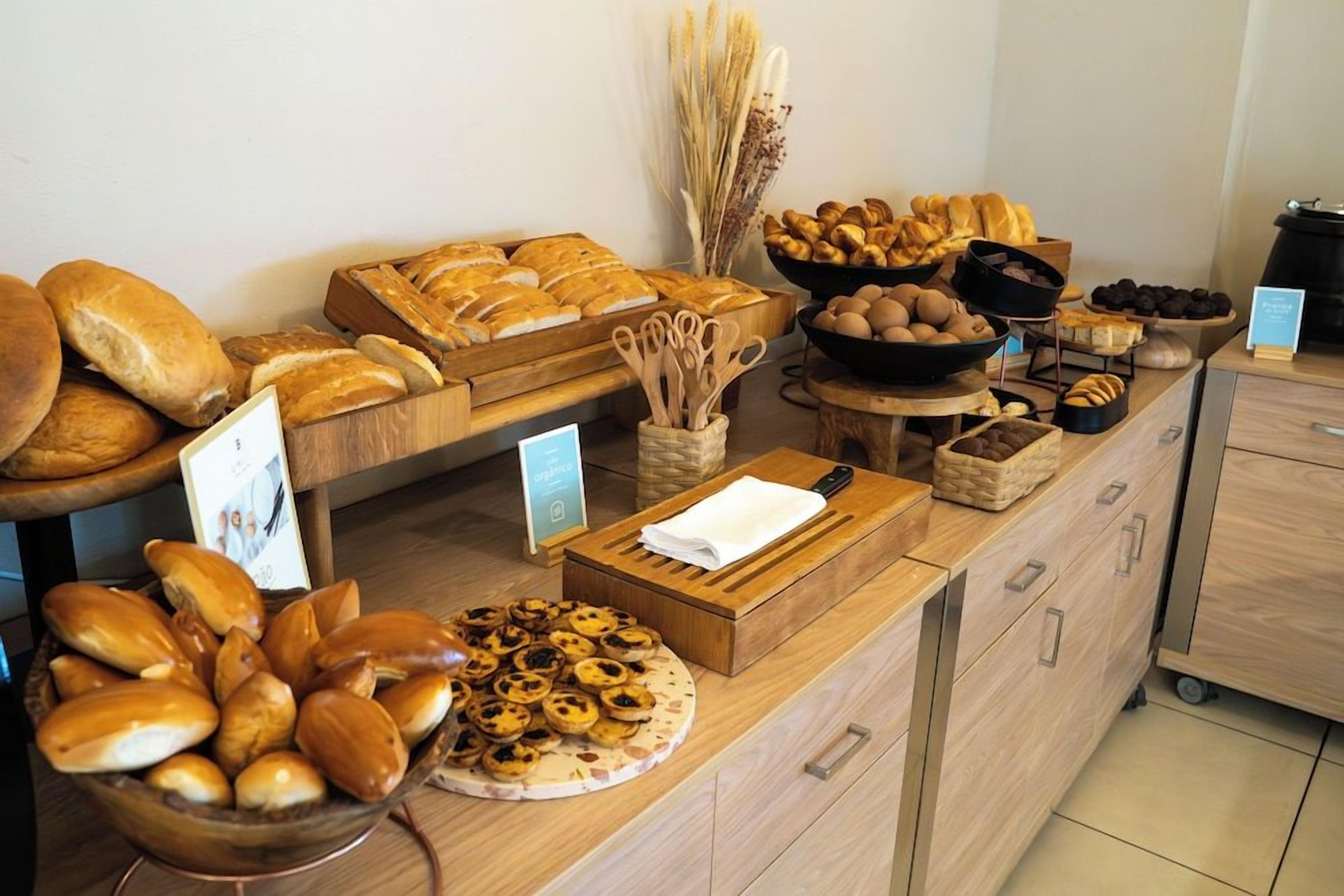 A buffet with various breads, pastries, and a cutting board with utensils.