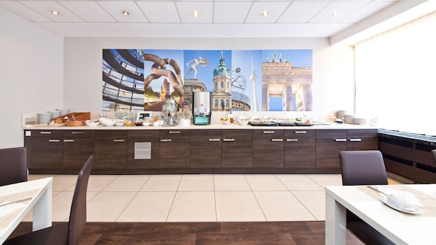 A modern hotel lobby with a large cityscape mural, a coffee station, and a seating area.