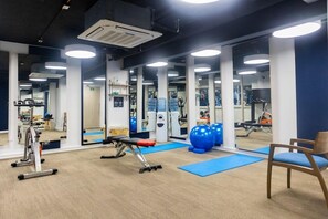 A gym with exercise equipment, mirrors, and blue mats. - Hotel Faranda Collection Cali (Cali)