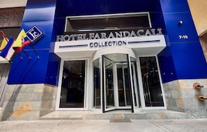 Hotellin sisäänkäynti, jossa on sininen julkisivu, pyörivät ovet ja kyltti, jossa lukee: ”HOTEL FARANDACALI COLLECTION”.