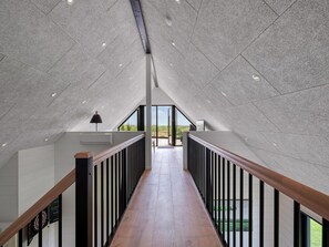 Ein modernes Interieur mit schrägverdeckter Decke, Holzboden und schwarzen Geländern.