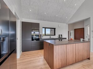 Eine moderne Küche mit einer zentralen Kochinsel, integrierten Geräten und Blick ins Freie.