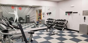 Uma academia com equipamentos de ginástica, piso xadrez e uma parede com um mural temático de fitness.