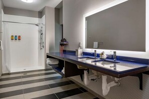 Ein modernes Badezimmer mit einem großen Spiegel, zwei Waschbecken und einer Duschkabine.