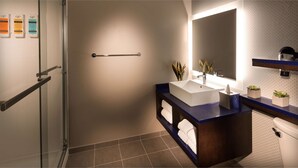 A modern bathroom with a glass shower enclosure, a vanity with a sink and mirror, and a toilet. - Glo Best Western Lexington (Lexington)